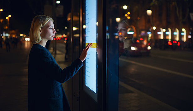 Frau tippt auf ein Display mit Touch-Funktion